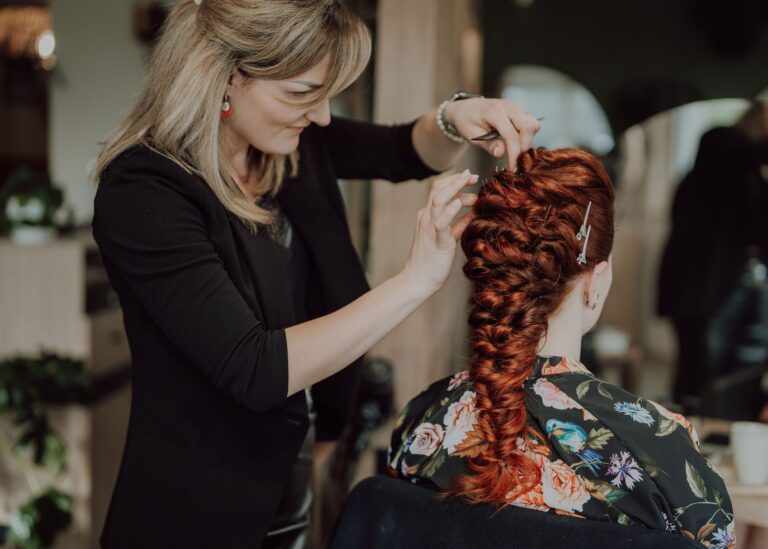 Coiffeuse réalisant une tresse sur cheveux roux au salon